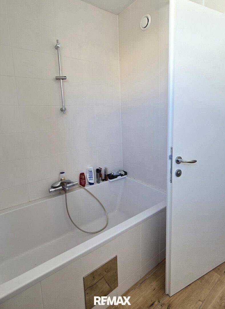 Badezimmer mit Badewanne und weißen Fliesen.
