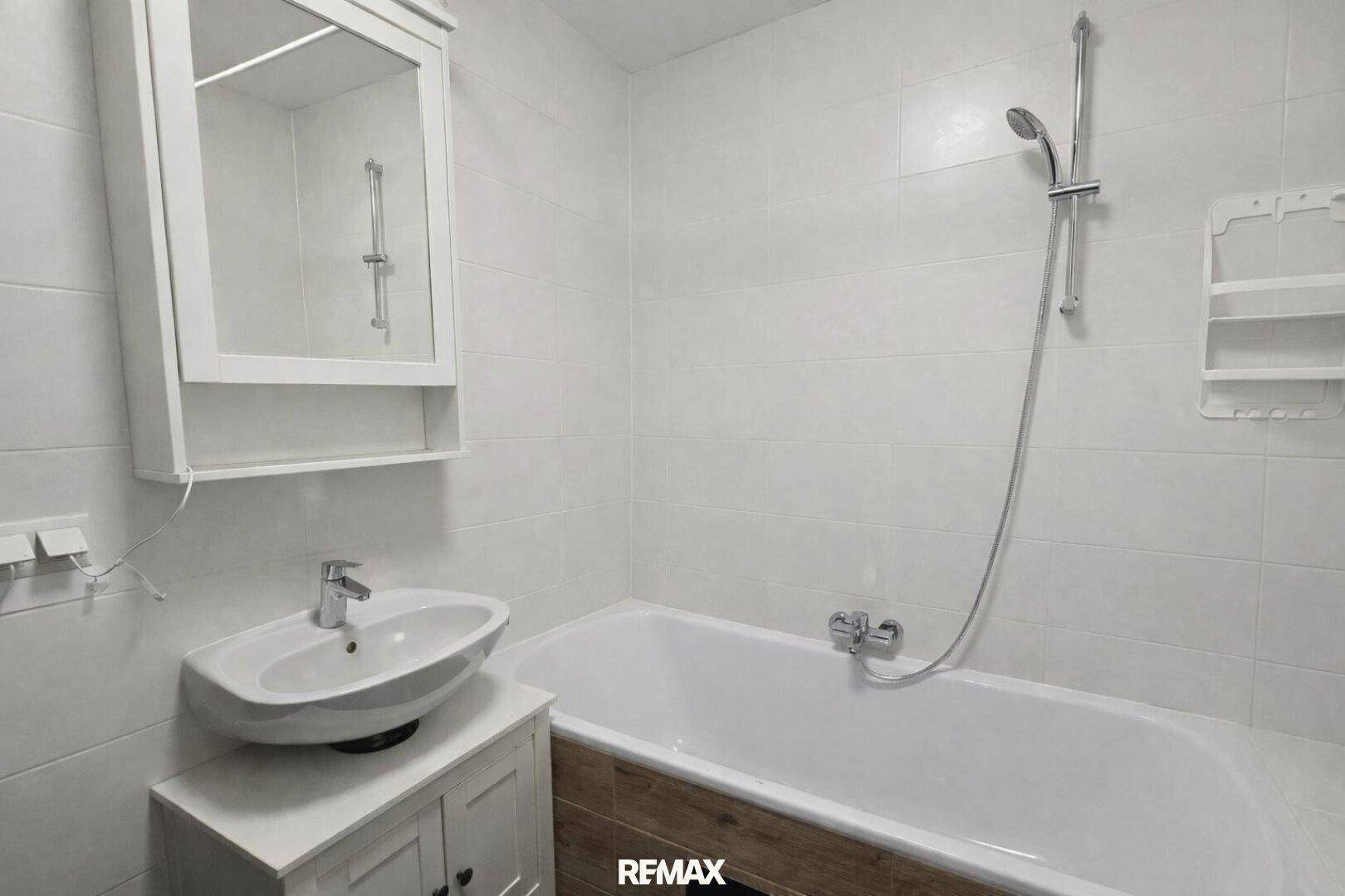 Helles Badezimmer mit Badewanne, Waschbecken und Spiegelschrank.