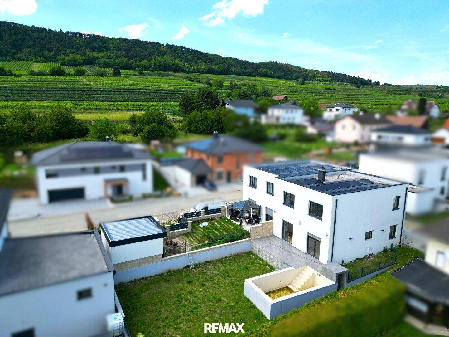 Luftaufnahme eines modernen Hauses mit Garten, Pool und Blick auf Weinberge.