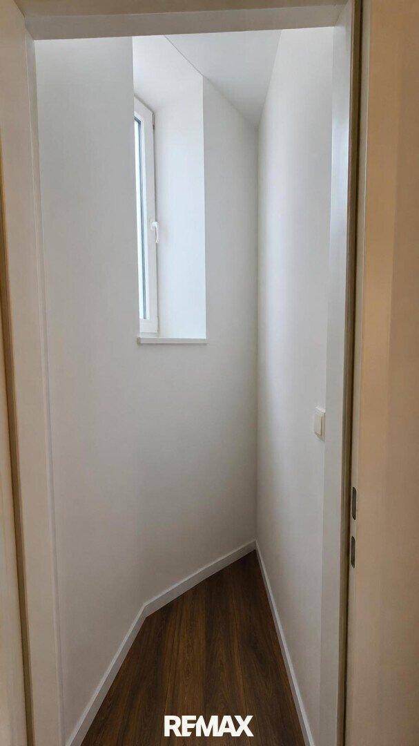 Schmaler Flur oder Nische mit Fenster und Holzboden.