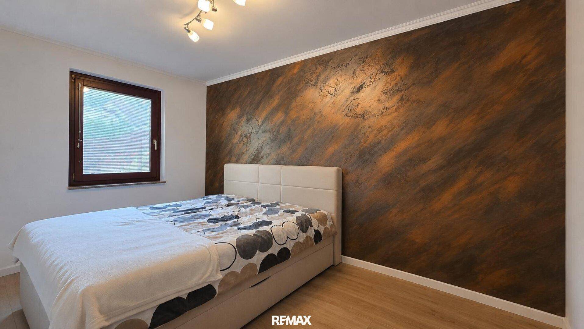 Schlafzimmer mit Doppelbett, dekorativer Wandgestaltung und hellem Holzboden.