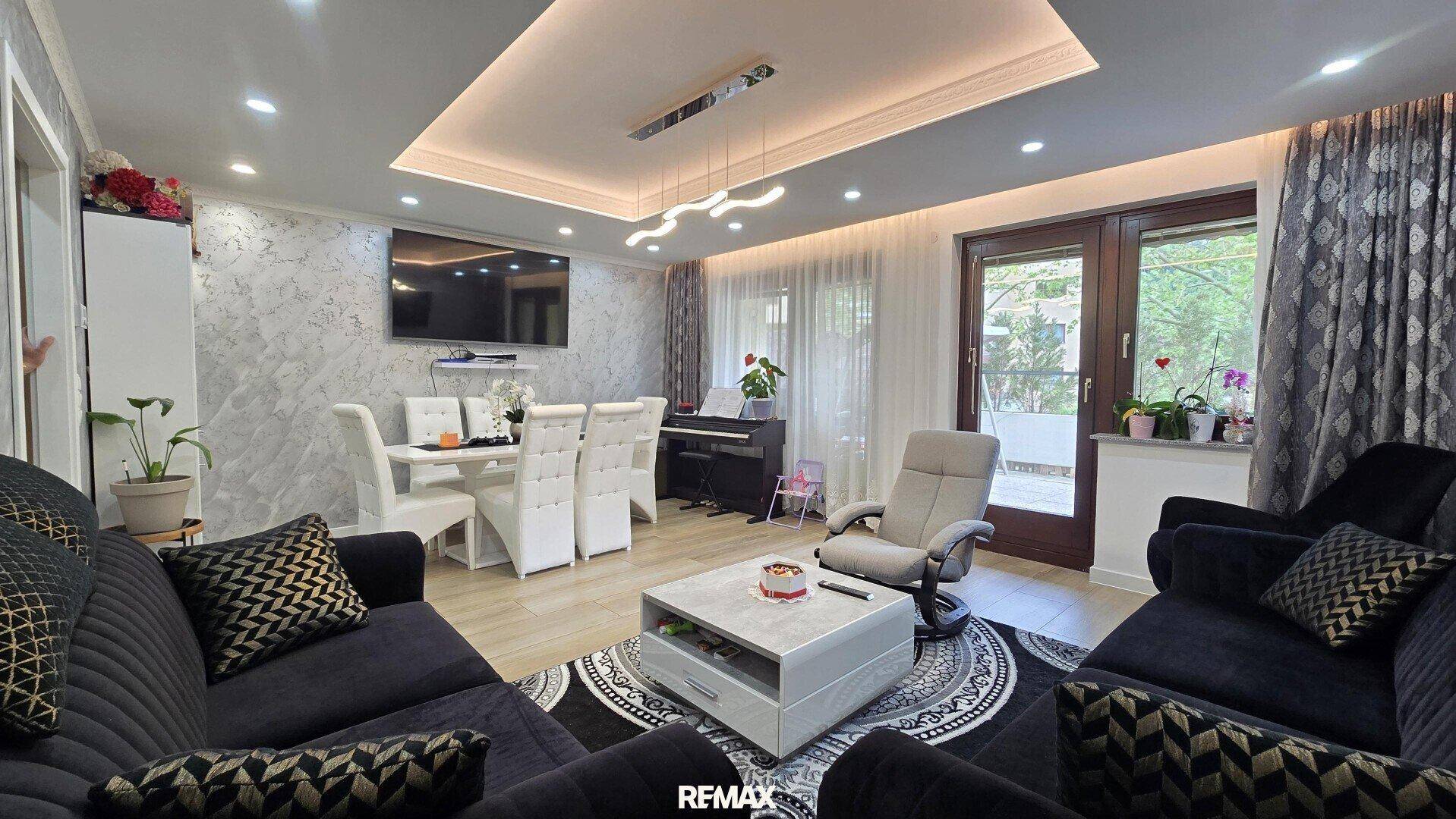Heller Wohn-Essbereich mit Zugang zur Terrasse, dunklen Sofas und modernem Design.
