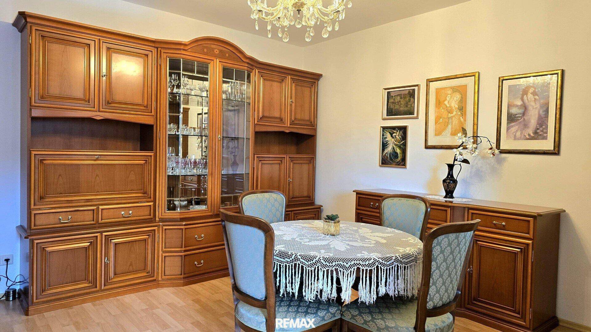 Detailansicht des Essbereichs mit elegantem Esstisch, Stühlen und einem großen Holzschrank.