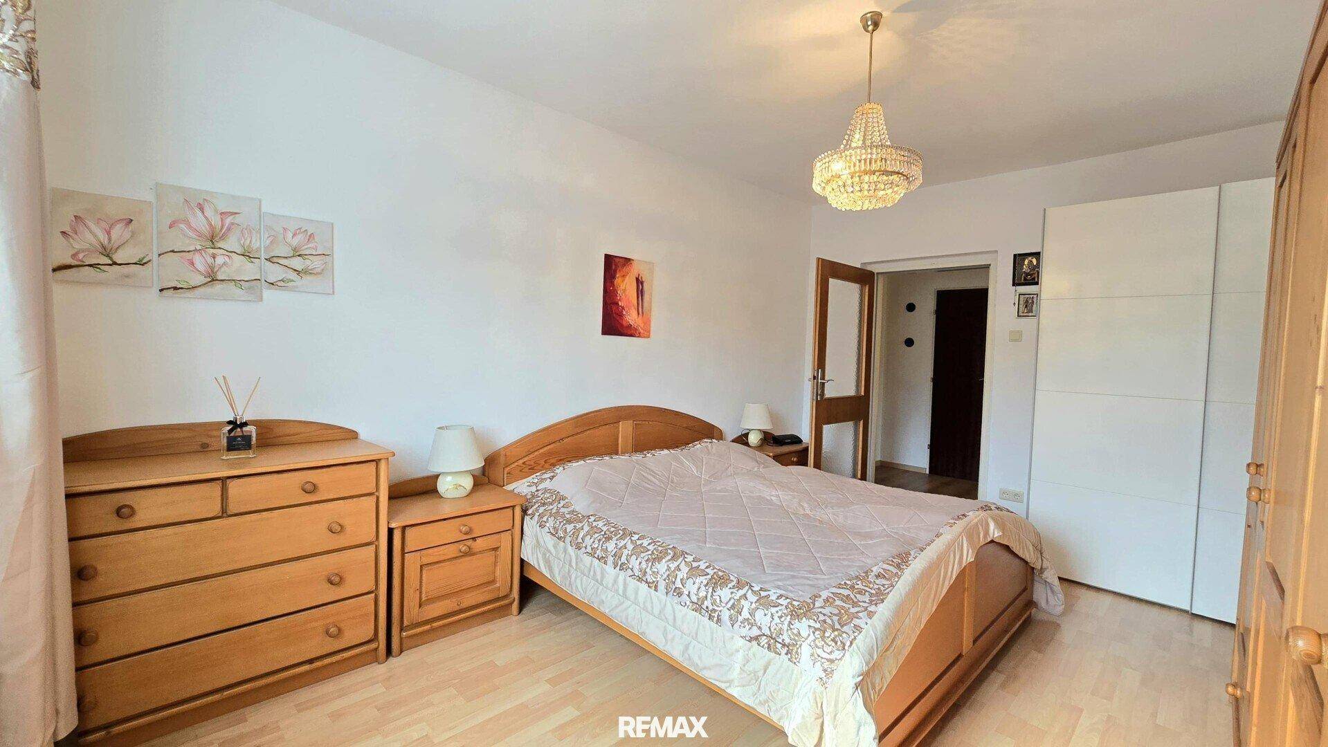 Gemütliches Schlafzimmer mit Doppelbett, Holzmöbeln und einem Kronleuchter.