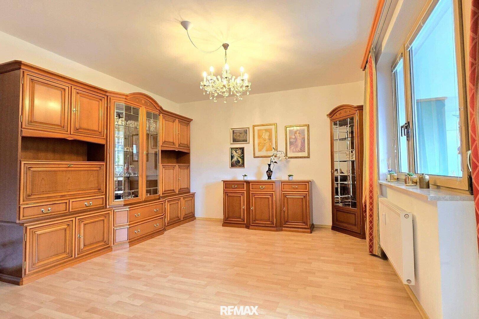 Geräumiges Wohnzimmer mit traditionellen Holzmöbeln, Laminatboden und einem Kronleuchter.