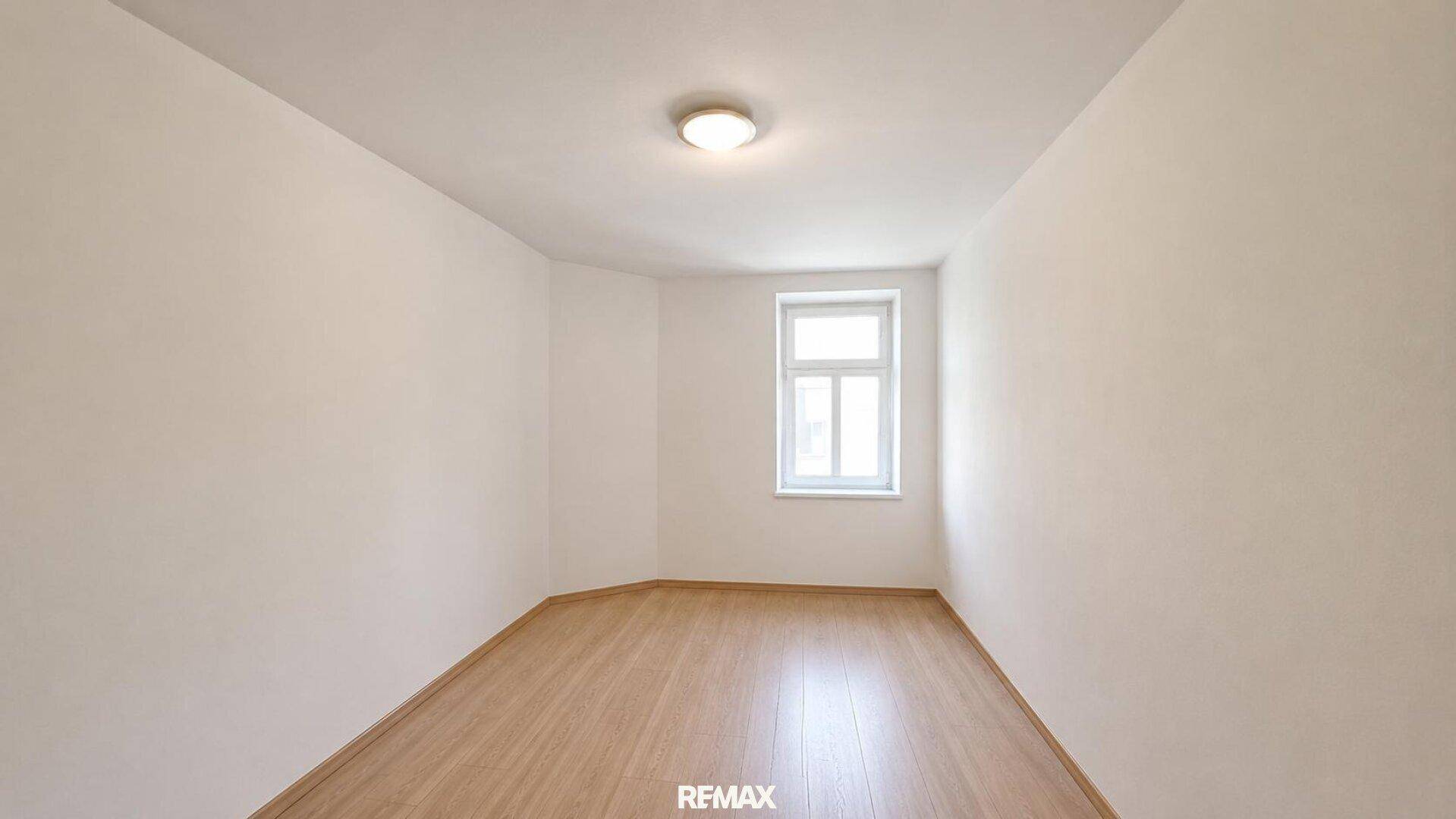 Helles, leeres Zimmer mit Laminatboden und einem Fenster, ideal als Schlaf- oder Arbeitszimmer.