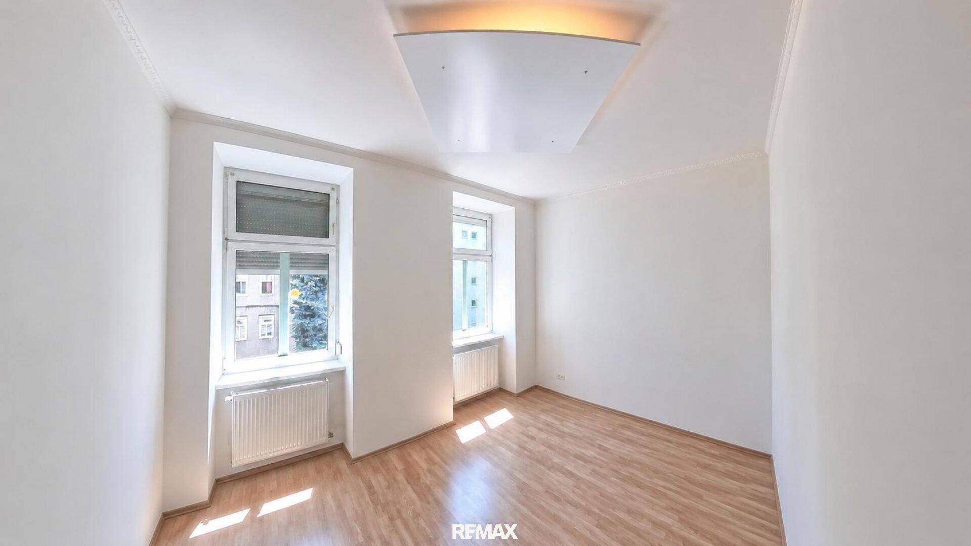 Leeres Zimmer mit zwei Fenstern und Laminatboden, bietet viel Tageslicht.