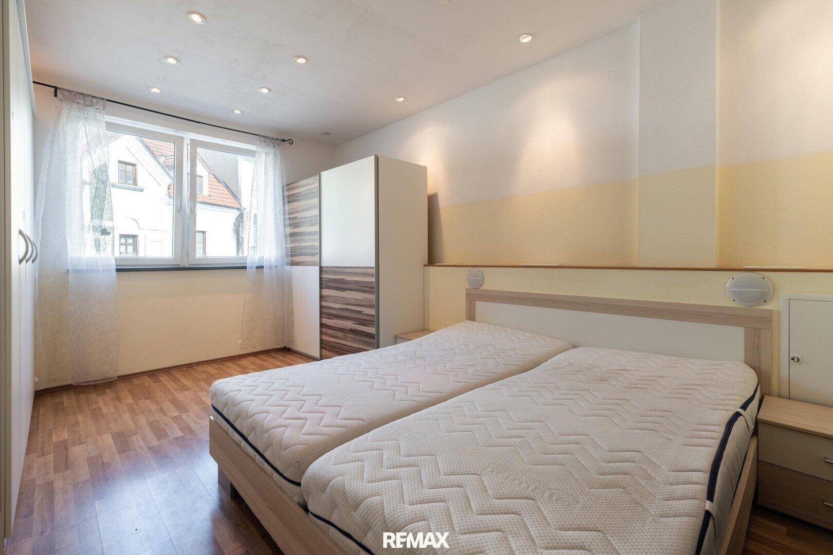 Schlafzimmer mit zwei Einzelbetten, Kleiderschrank und Blick aus dem Fenster.