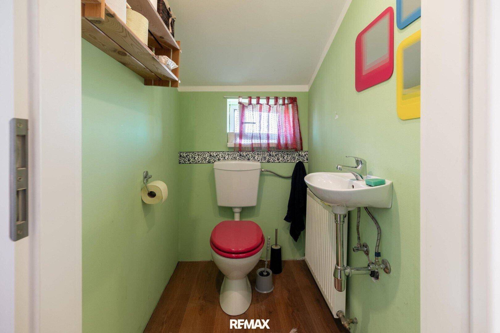 Helles WC mit grünen Wänden, Toilette und kleinem Waschbecken.