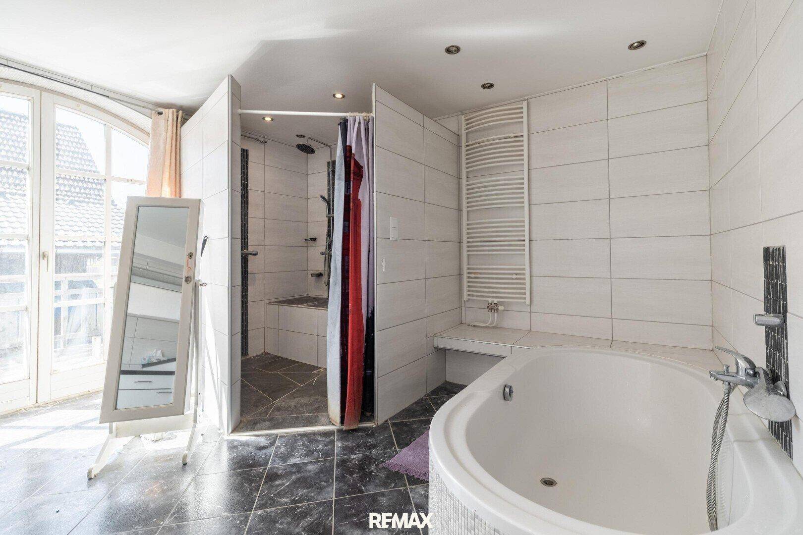 Geräumiges Badezimmer mit Badewanne, Duschbereich und Zugang zum Balkon.