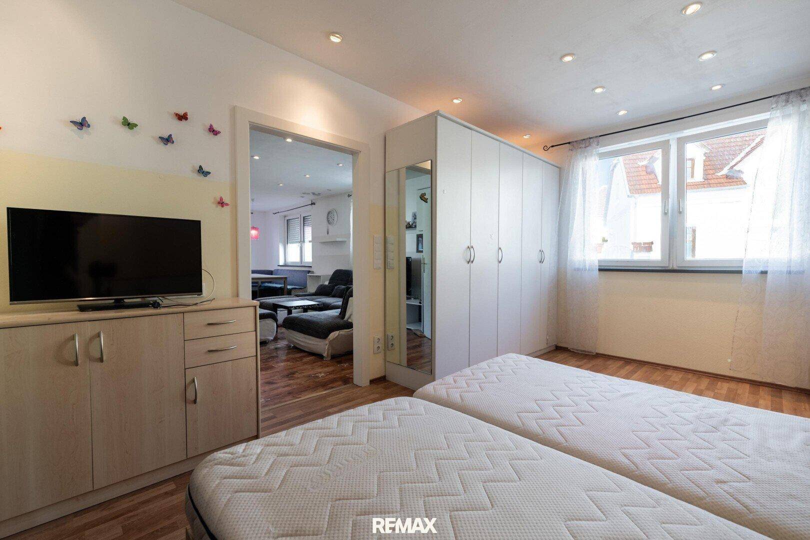 Schlafzimmer mit Betten, Kleiderschrank und offenem Zugang zum Wohnbereich.
