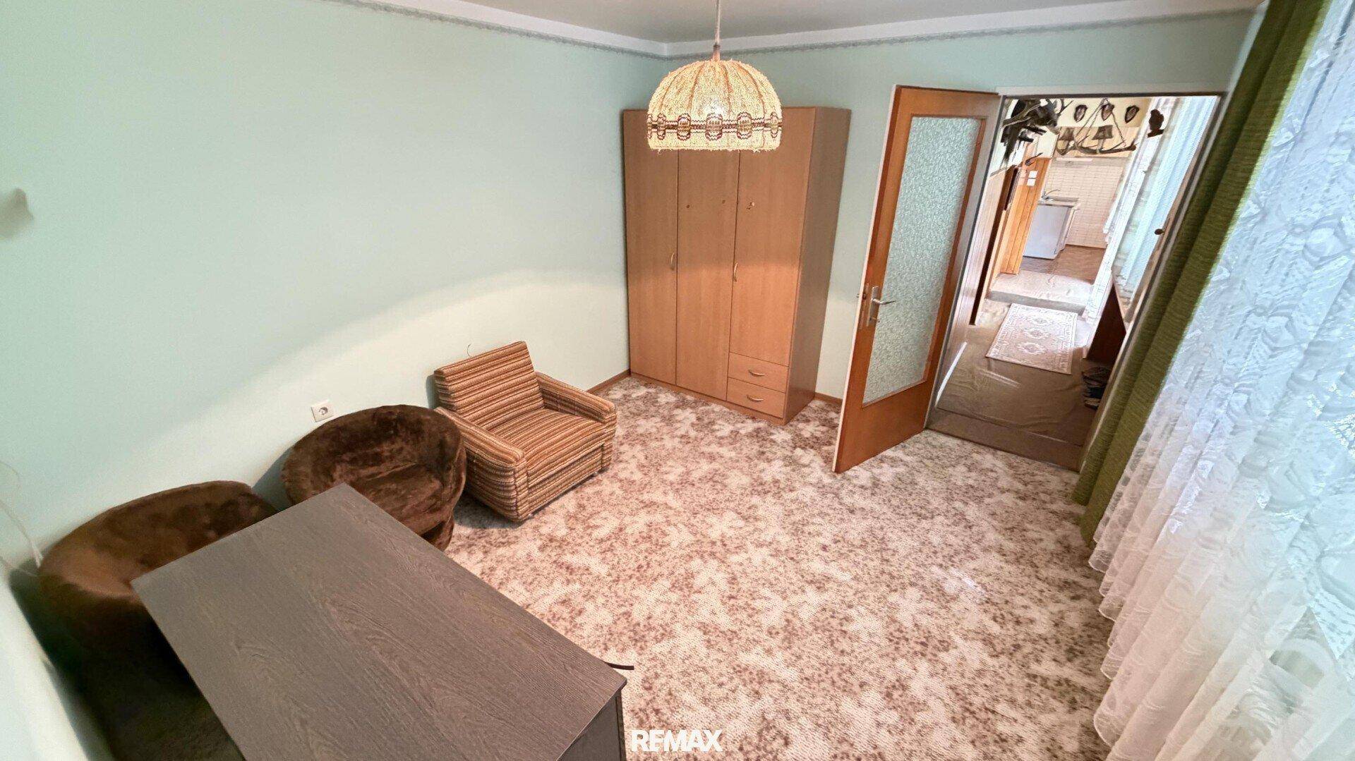 Schlafzimmer mit Teppichboden, Kleiderschrank und bequemen Sesseln.