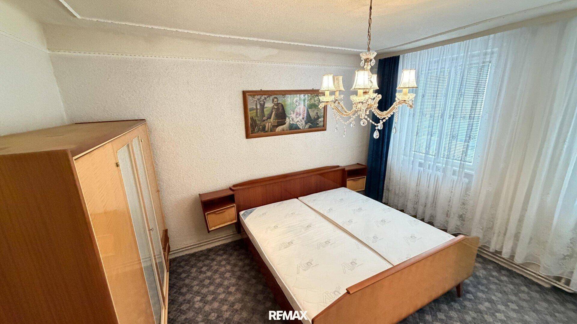Schlafzimmer mit Doppelbett, Nachttischen und einem klassischen Kronleuchter.