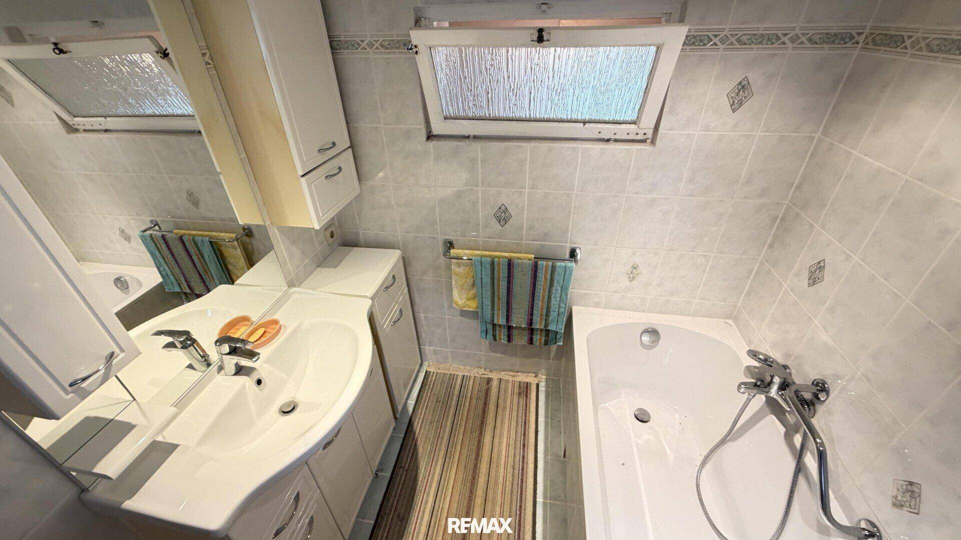 Badezimmer mit Badewanne, Waschbecken und einem praktischen Dachfenster.