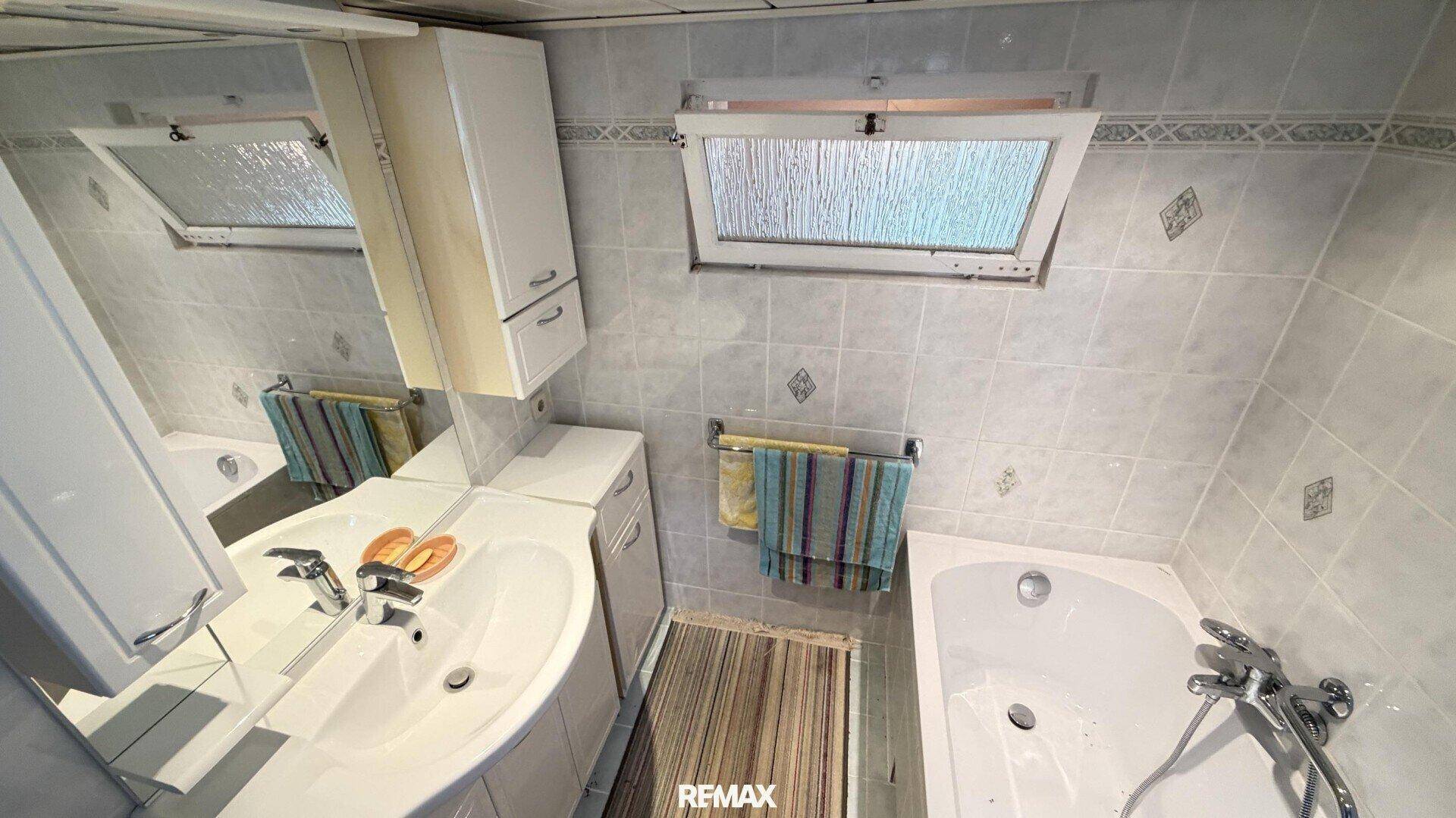 Badezimmer mit Badewanne, Waschbecken und einem praktischen Dachfenster.
