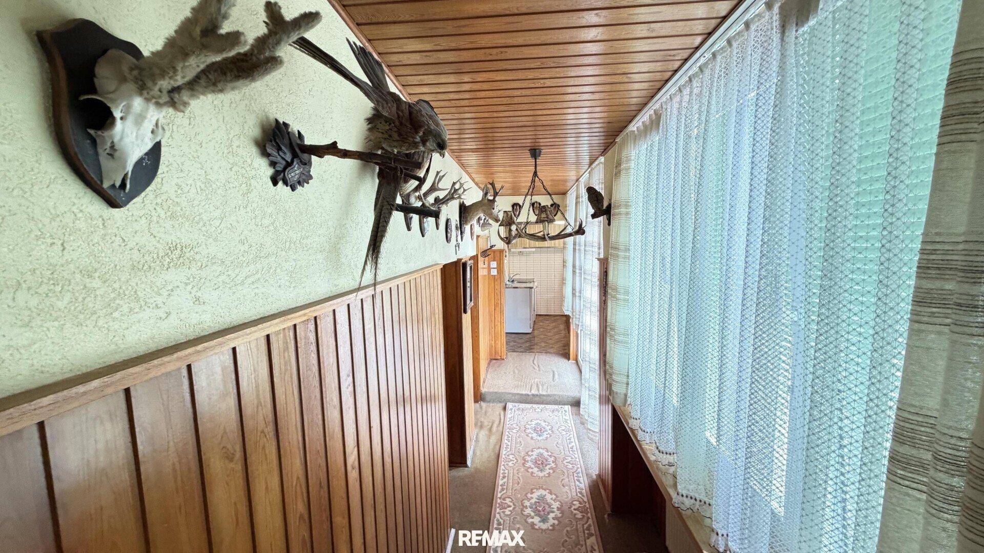 Flur mit Holzvertäfelung, Treppe und Jagdtrophäen an der Wand.