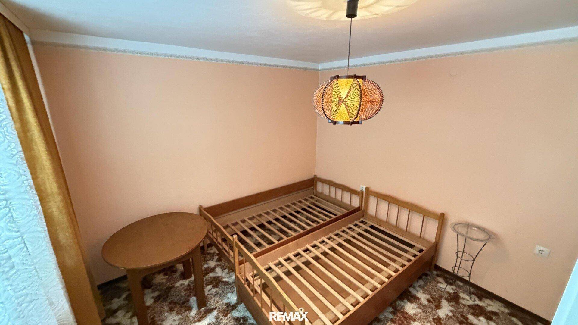 Schlafzimmer mit zwei Einzelbetten und einem runden Holztisch.