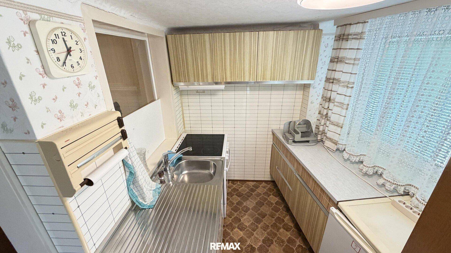 Kleine Küche im Retro-Stil mit Holzschränken, Fliesen und kariertem Boden.
