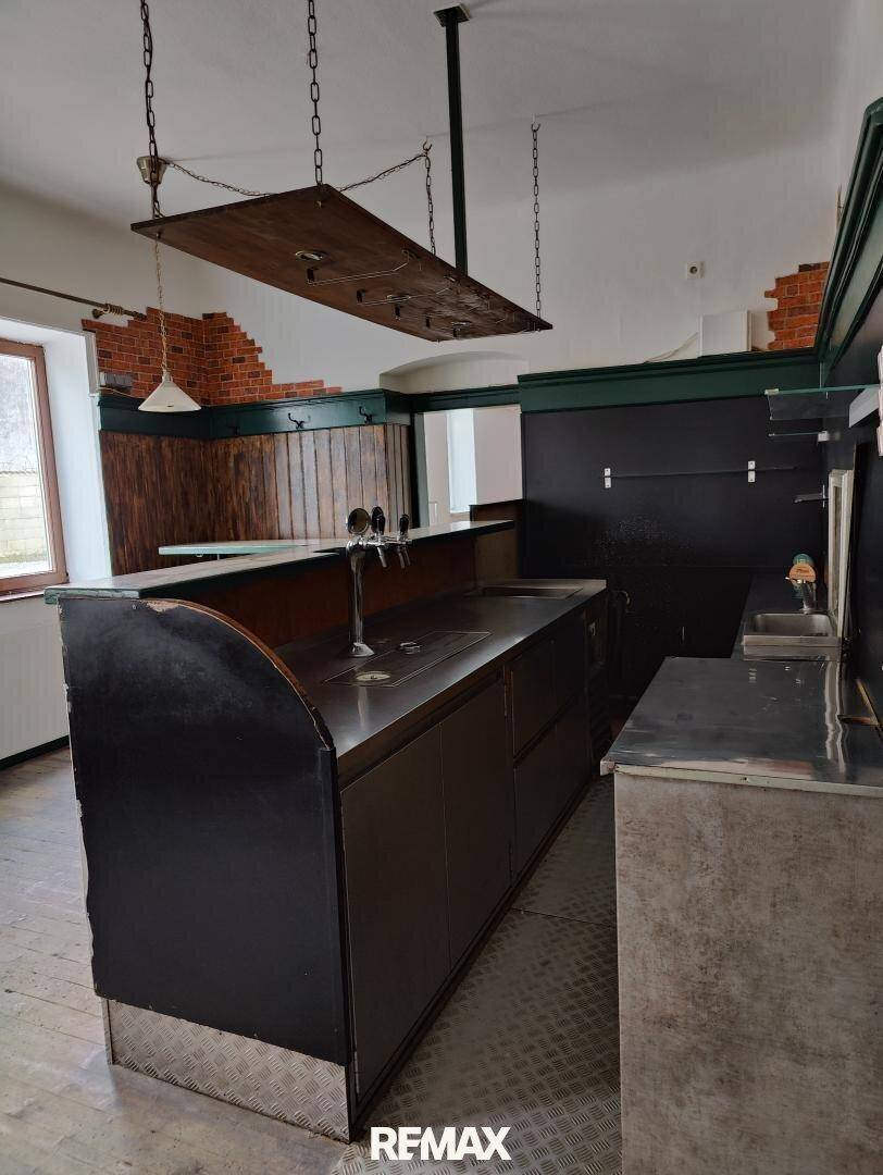 Barbereich mit Edelstahloberflächen, Zapfanlage und rustikalen Holzelementen an den Wänden.