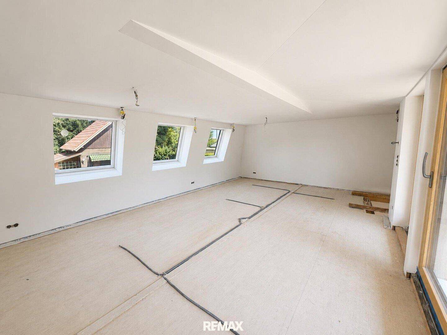 Heller Raum im Obergeschoss mit Dachfenstern und vorbereiteten Installationen für den Innenausbau.