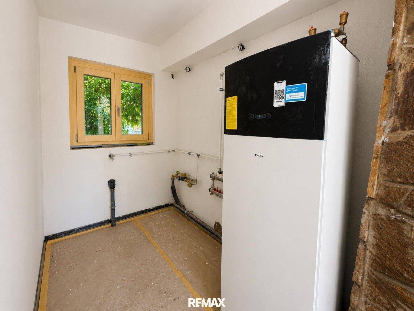 Technikraum mit moderner Wärmepumpe und einem Fenster für natürliche Belüftung.