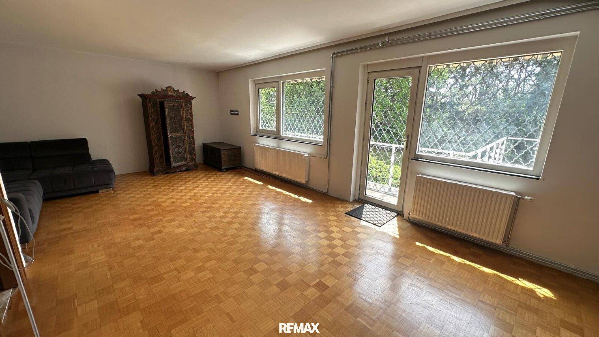 Helles Wohnzimmer mit Parkettboden, traditionellen Möbeln und Zugang zu einem französischen Balkon.