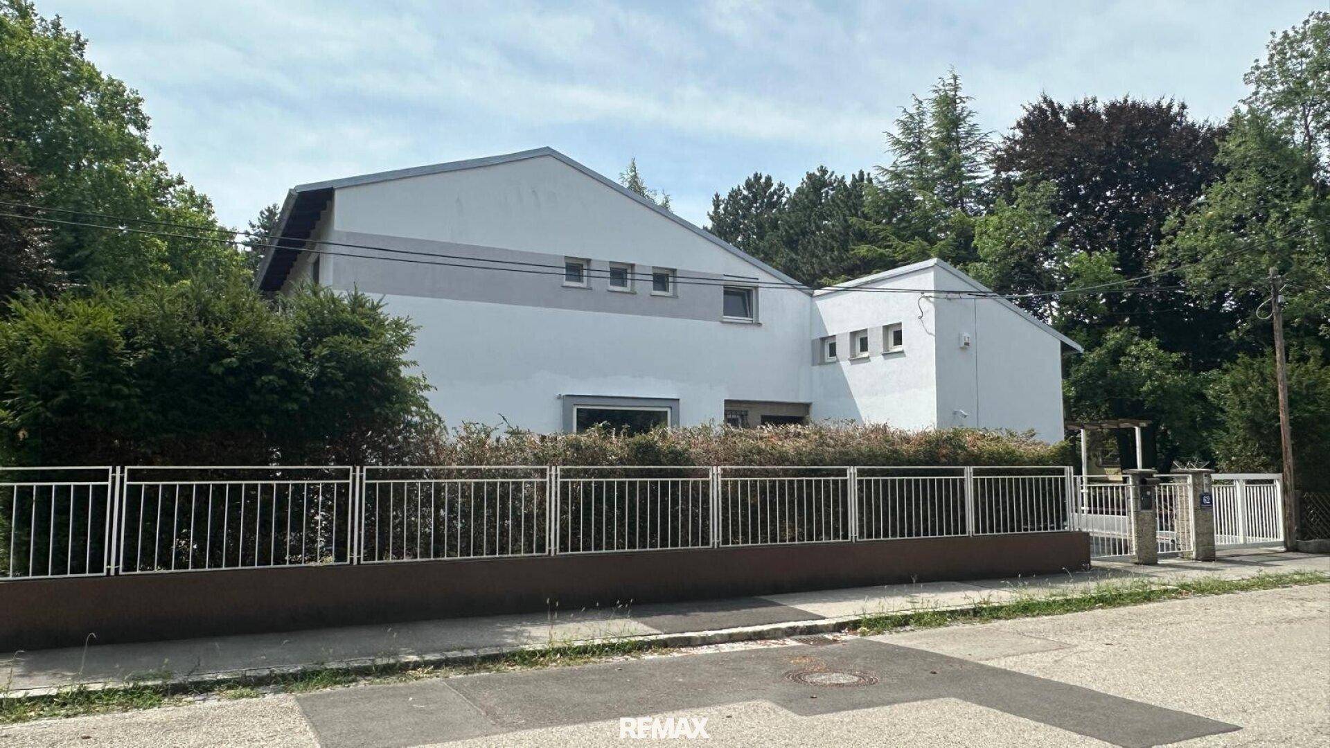 Ansicht des modernen Einfamilienhauses von der Straße mit Zaun und Zufahrt.