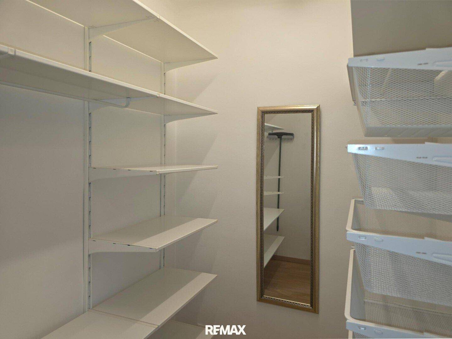 Praktischer begehbarer Kleiderschrank mit Regalsystemen und einem Spiegel für optimale Organisation.