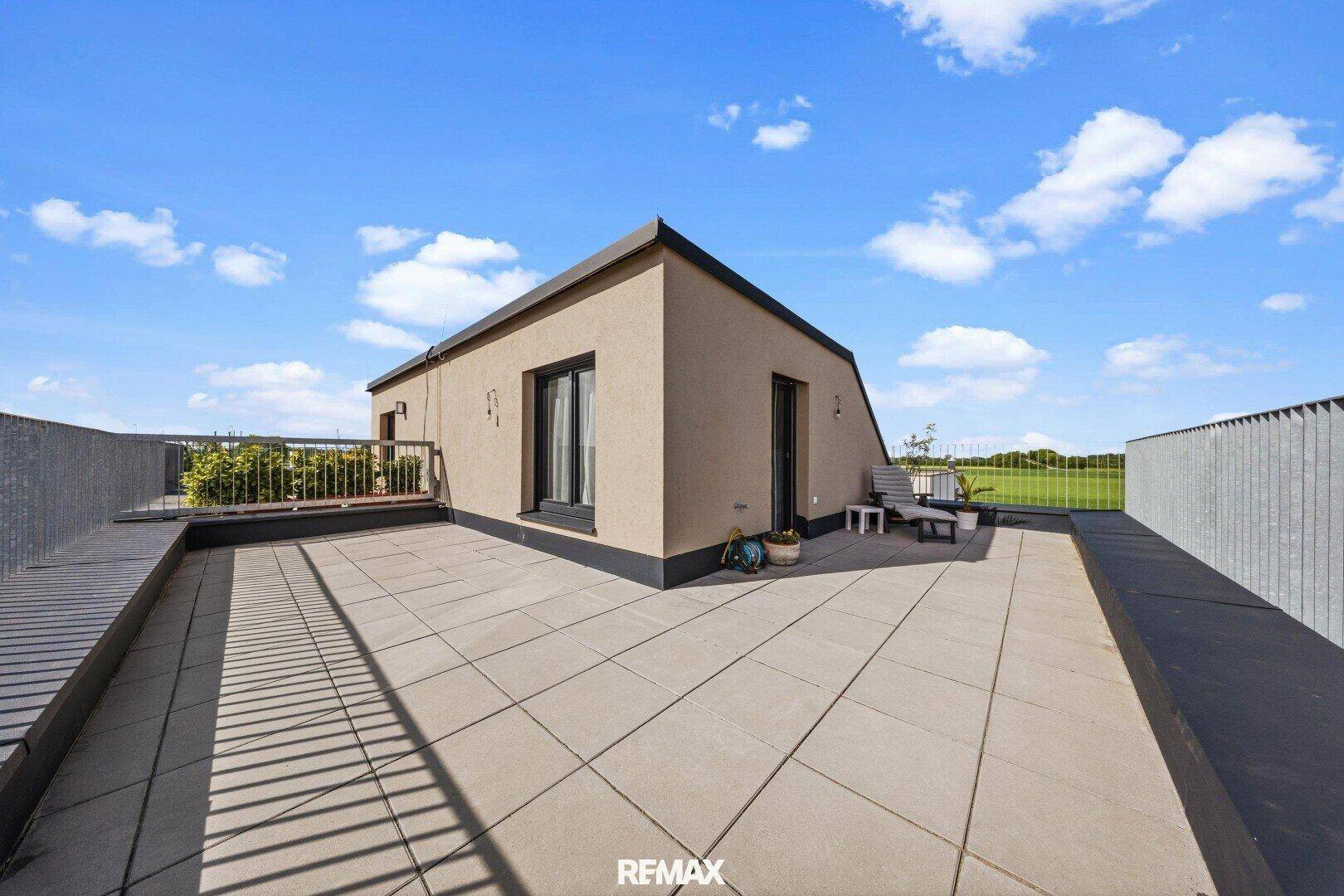 Weitläufige Dachterrasse mit Fliesenboden und freiem Blick auf die umliegende grüne Landschaft.