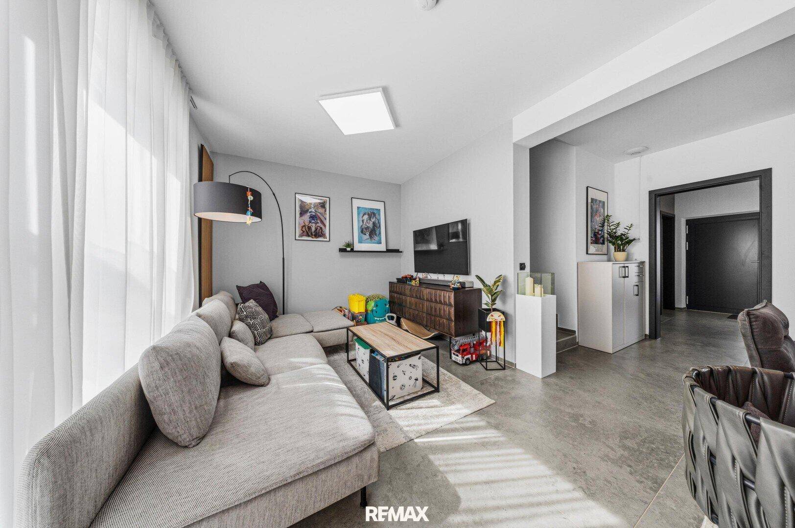 Heller Wohnbereich mit bequemer Couch, modernem Dekor und Zugang zum Flur.