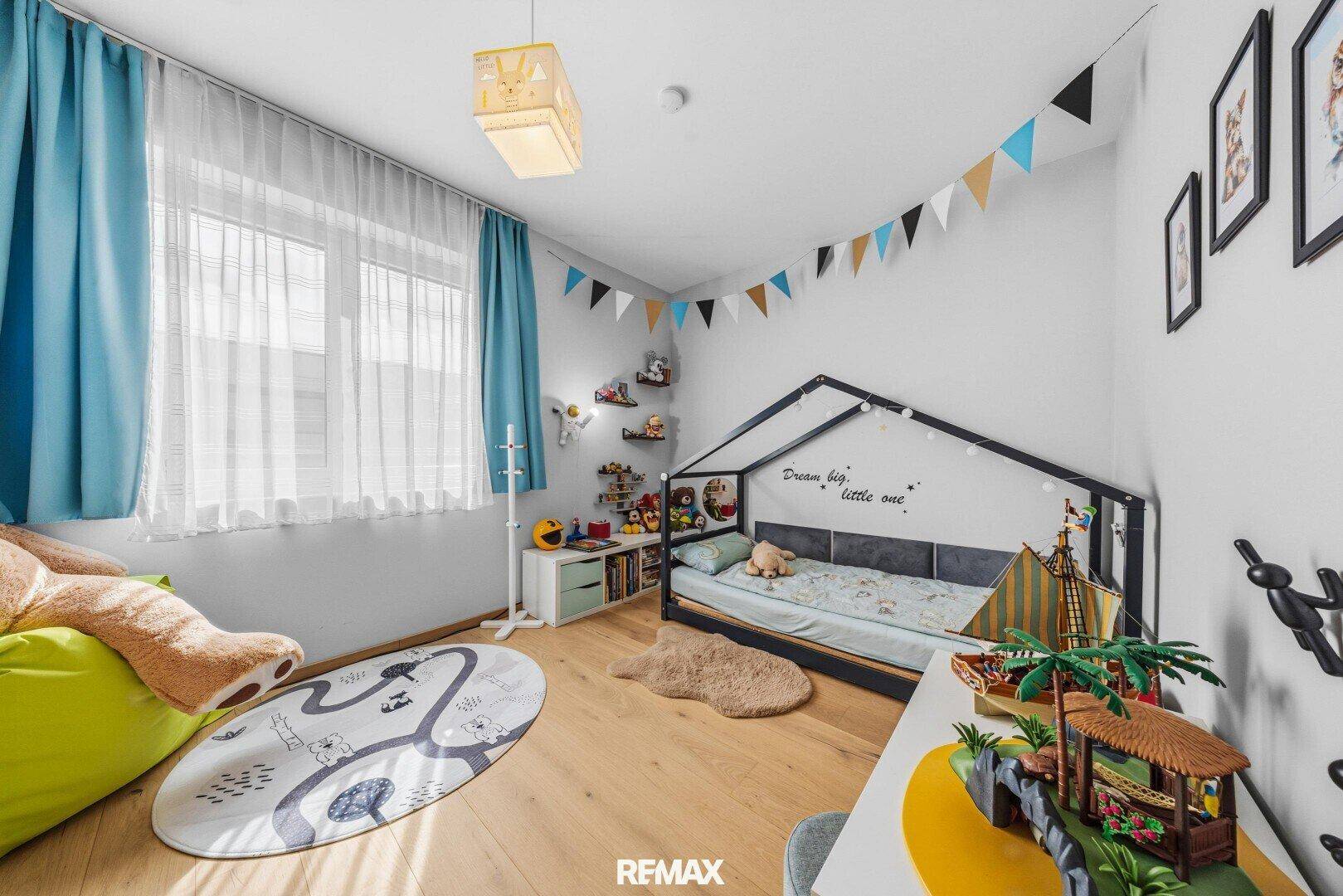 Freundliches Kinderzimmer mit Holzboden, Spielbereich und bunten Dekorationen.