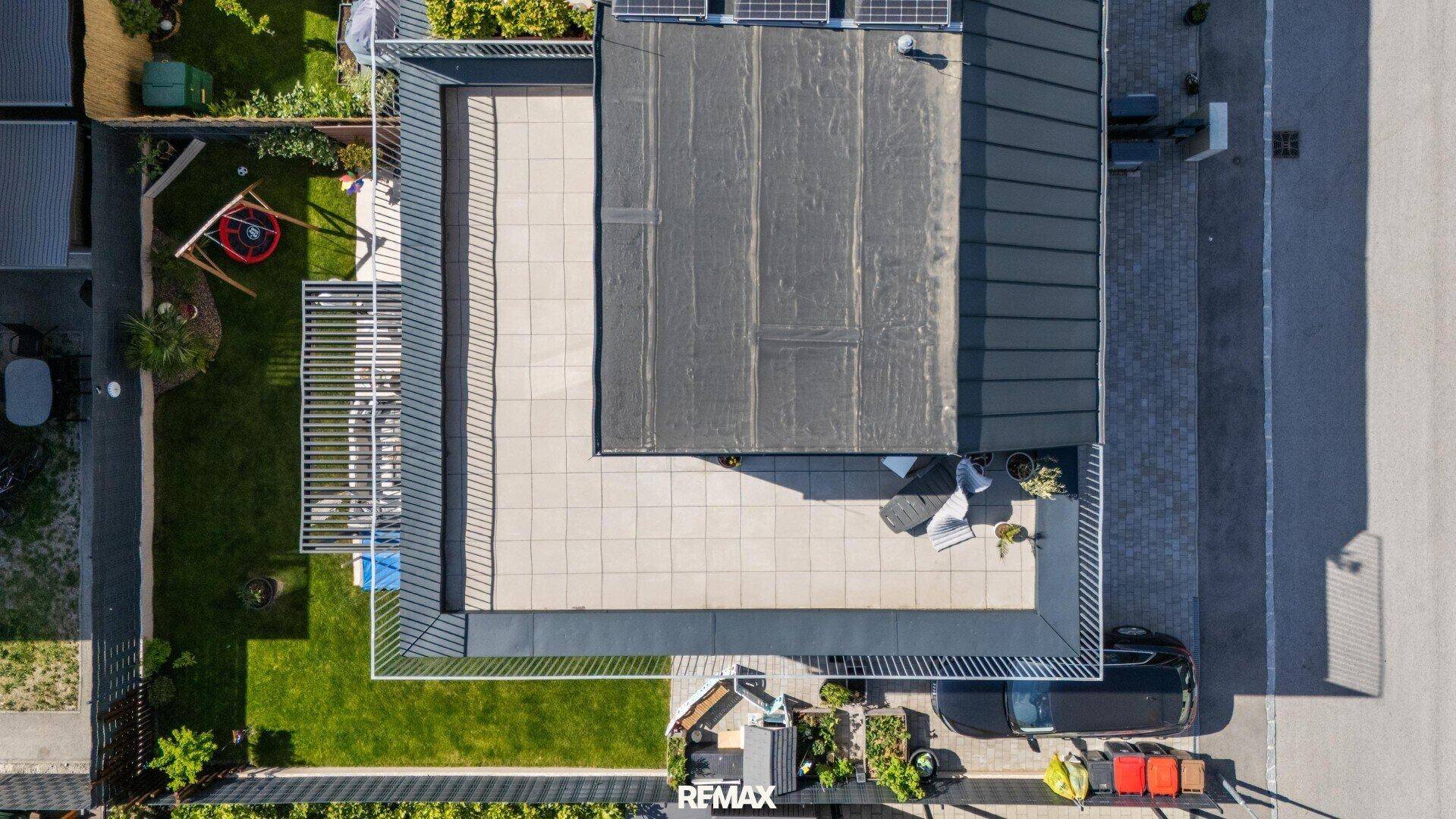 Draufsicht auf das Anwesen mit Dachterrasse, Garten, Einfahrt und Solaranlage auf dem Dach.