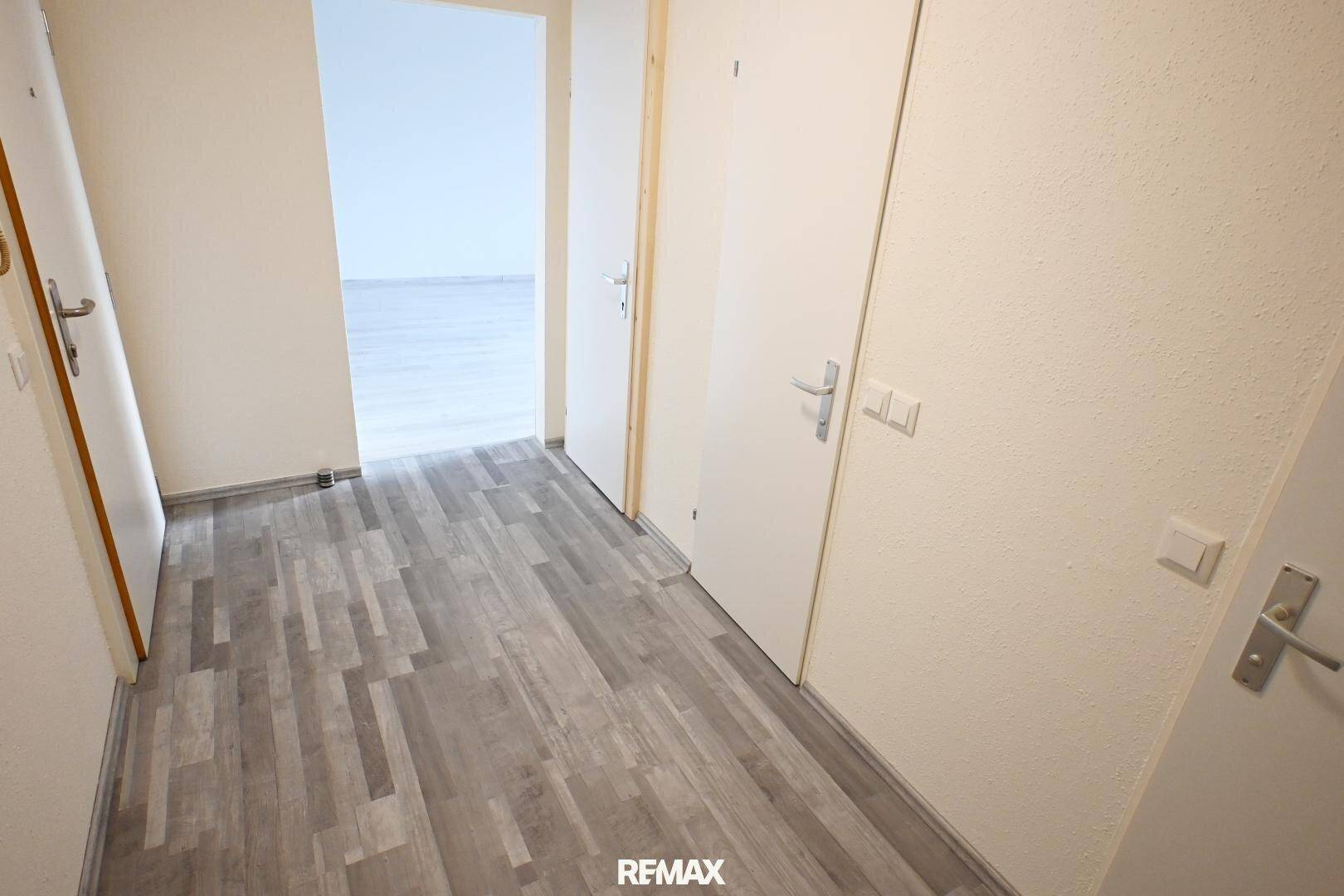 Heller Flur mit Laminatboden und mehreren Türen, der verschiedene Räume verbindet.