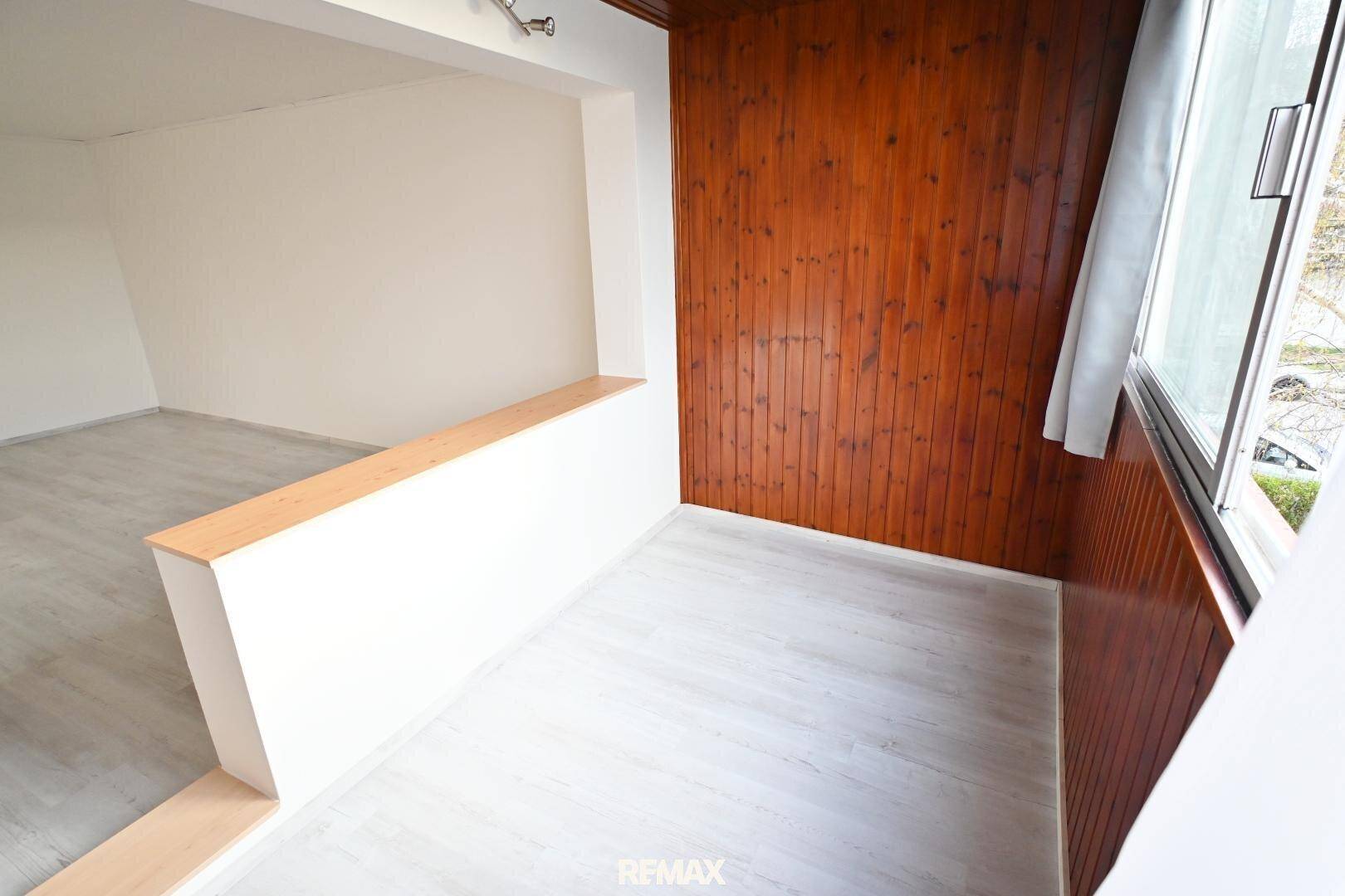 Verglaste Loggia mit Holzverkleidung an Wand und Decke sowie hellem Laminatboden.