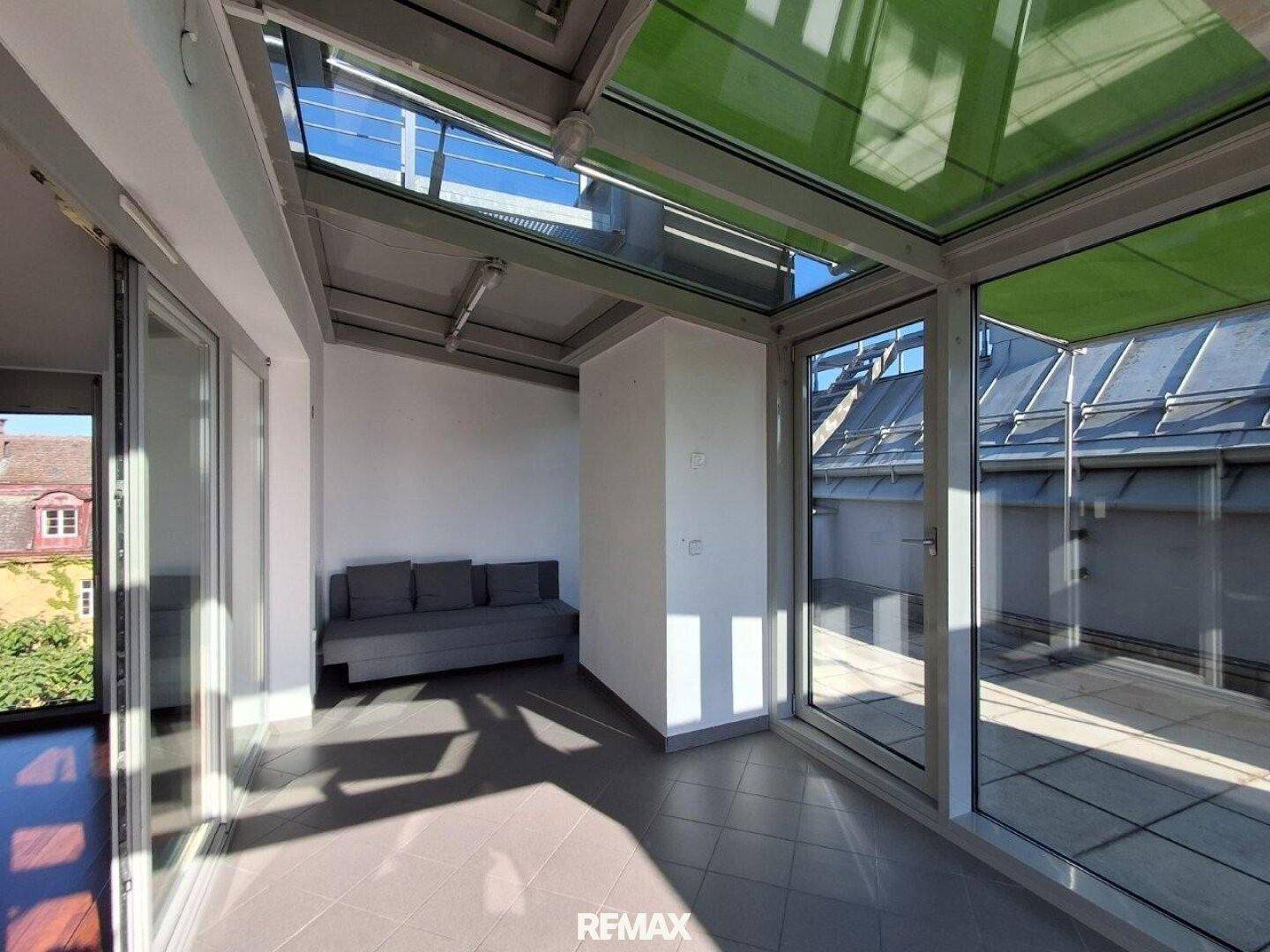 Heller Wintergarten mit integrierter Sitzbank und Glasfronten, die zur Terrasse führen.