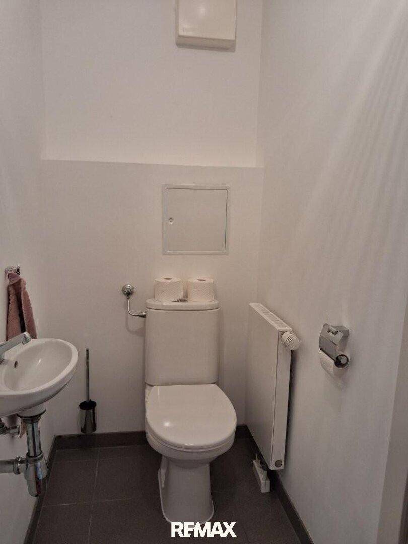 Kleines Gäste-WC mit Toilette und Handwaschbecken, funktional und hell gestaltet.