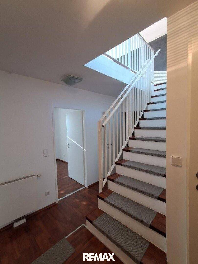 Helle Treppe mit Teppichstufen, die vom Flur in die obere Etage des Hauses führt.