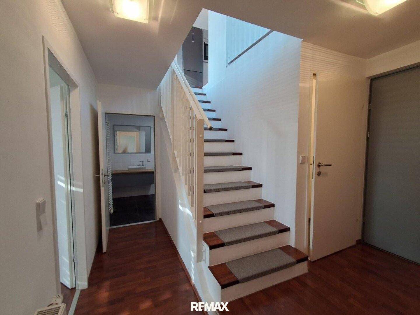 Geräumiger Flur mit Treppe und Zugang zu weiteren Räumen, hell und einladend.