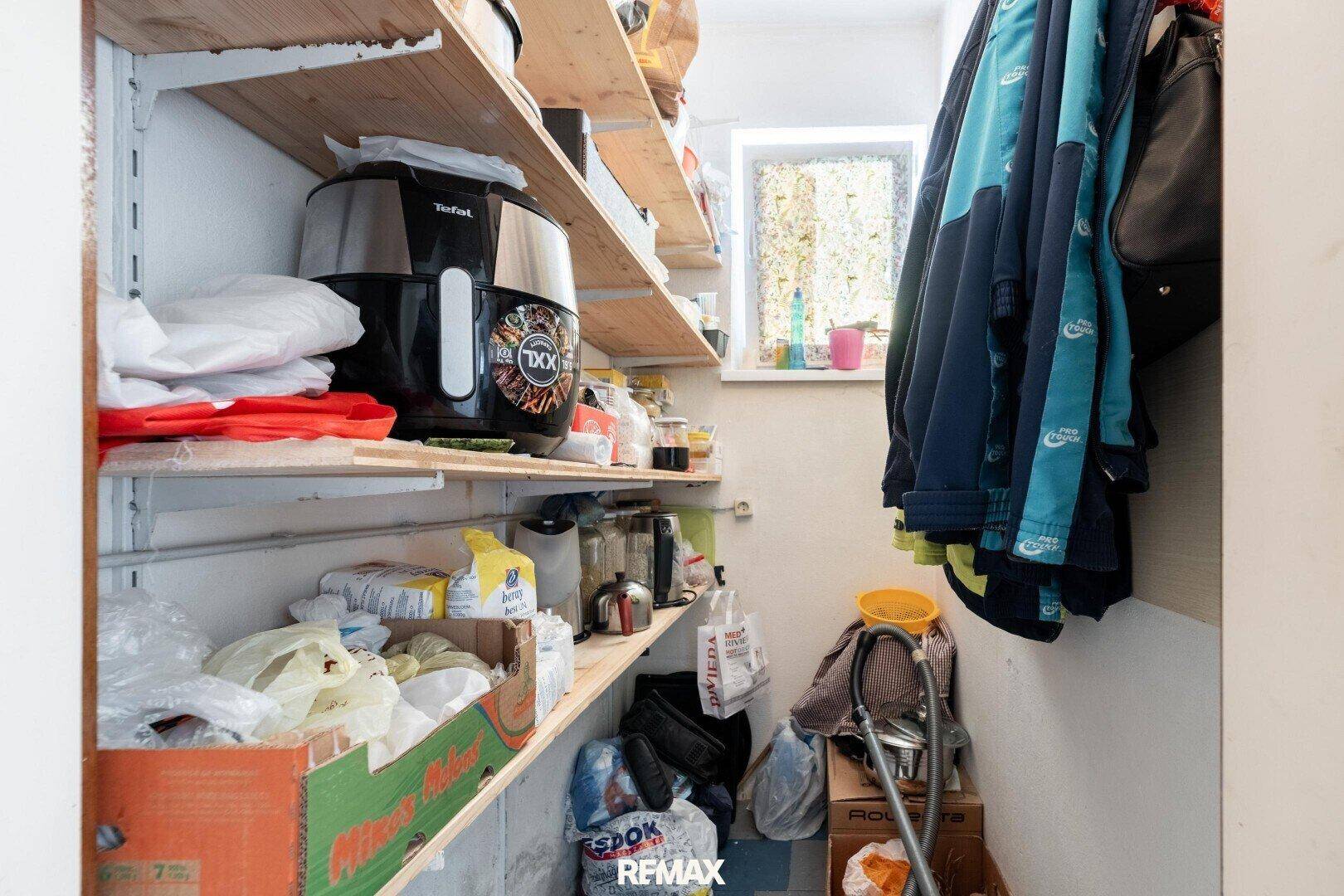 Praktische Speisekammer mit Regalen voller Vorräte und einem kleinen Fenster.
