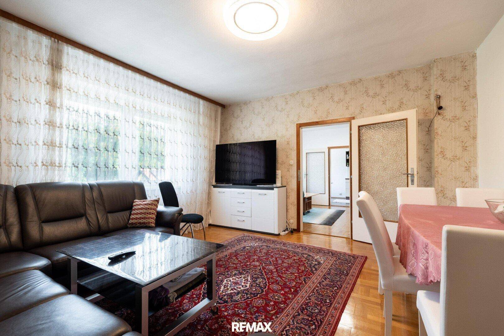 Geräumiger Wohn-Essbereich mit Ledersofa, Esstisch und großem Fernseher.