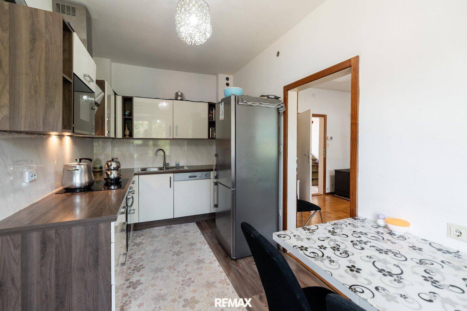 Moderne Küche mit zweifarbigen Schränken, Kühlschrank und Essbereich.