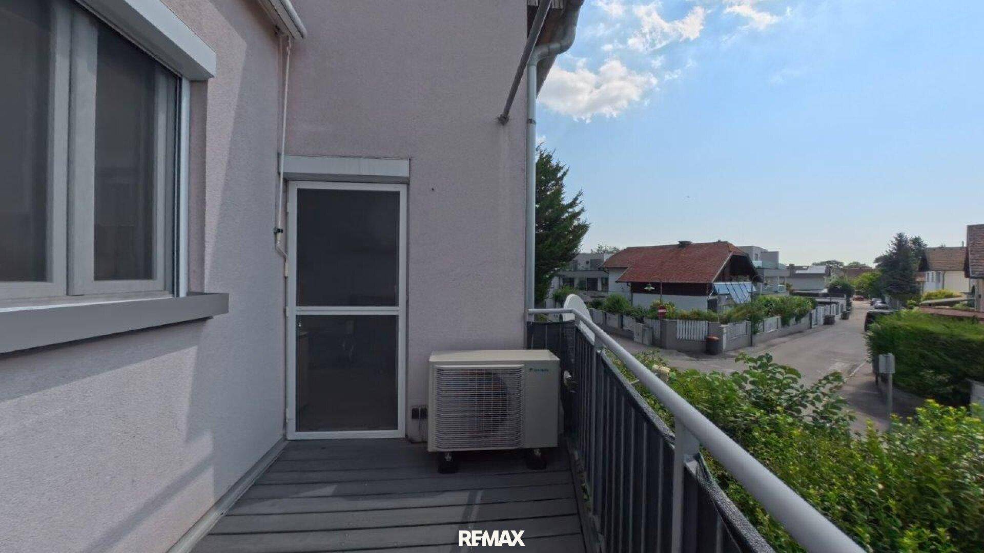 Balkon mit Holzboden, Geländer und Blick auf die umliegende Nachbarschaft.