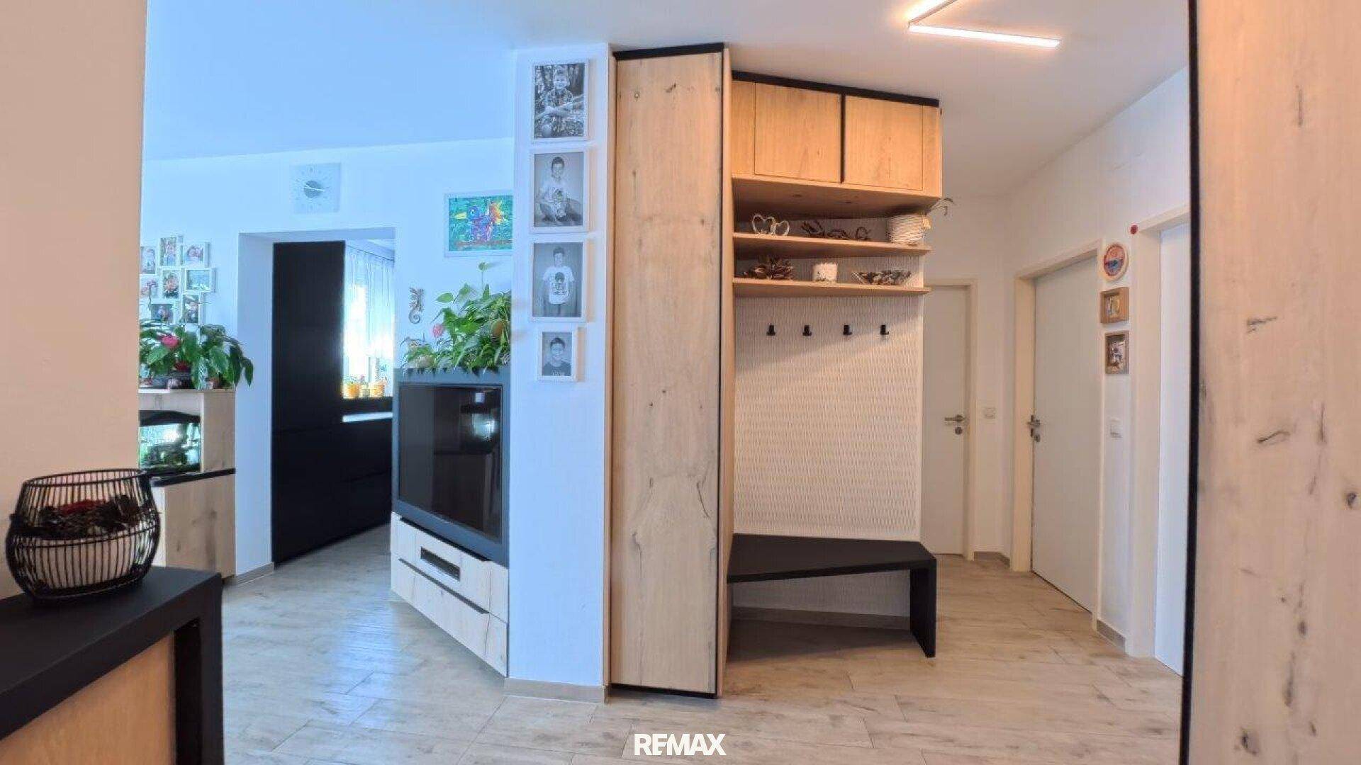 Heller Flur mit Holzelementen, Garderobe und integriertem TV-Möbel im Eingangsbereich.