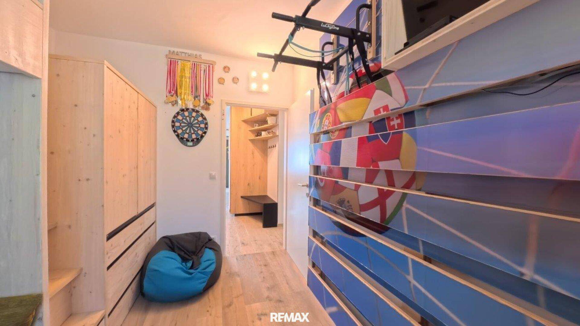 Helles Jugendzimmer mit Holzelementen, Sportausrüstung und Zugang zum Flur.