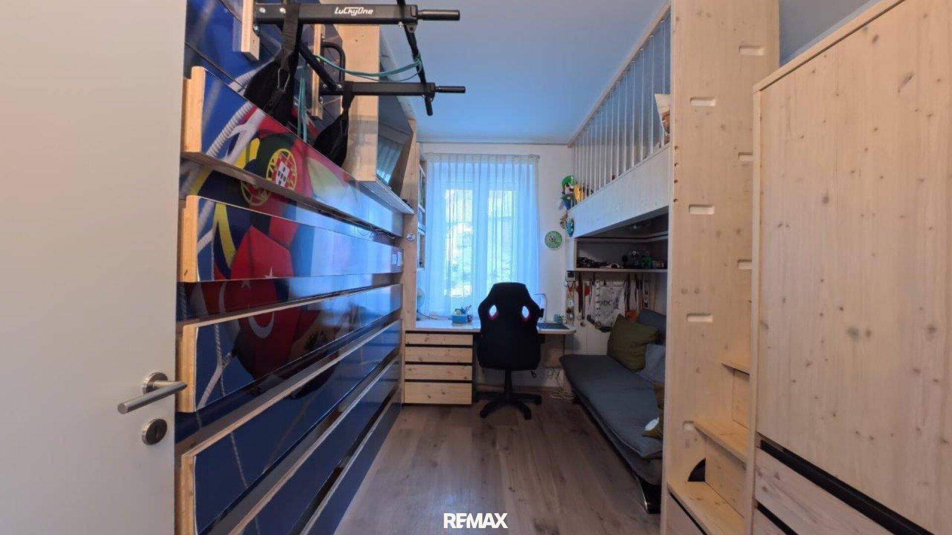 Jugendzimmer mit Hochbett, Schreibtisch und sportlichen Dekorationselementen.