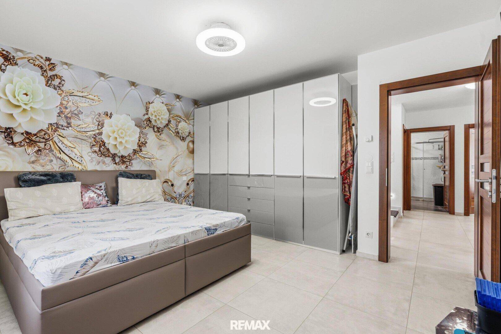 Schlafzimmer mit großem Doppelbett, dekorativer Wandtapete und Einbauschränken.