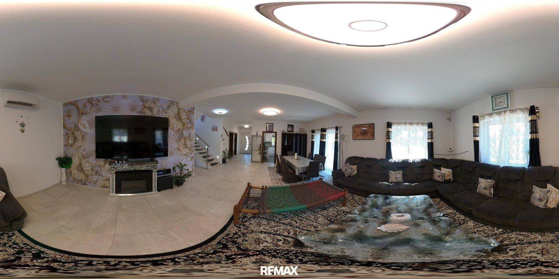 Geräumiges Wohnzimmer mit großem Sofa, Fliesenboden und dekorativer Wandtapete.
