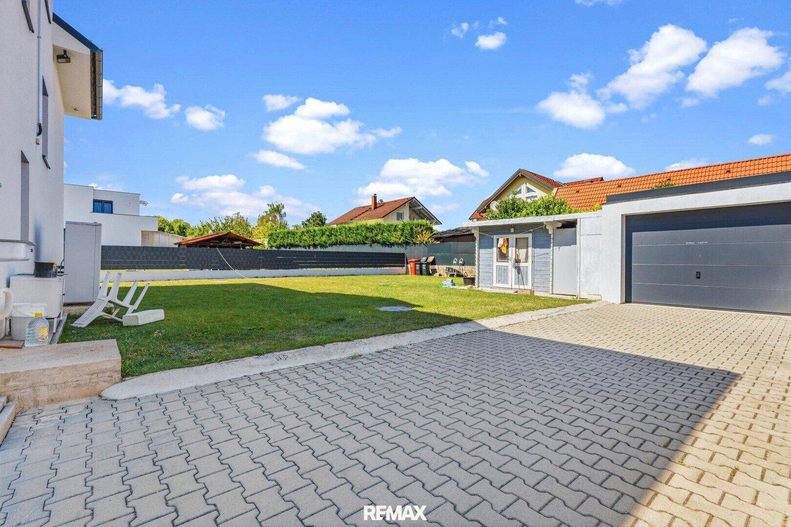 Großer, gepflegter Gartenbereich hinter dem Haus mit Rasenfläche und separater Garage.