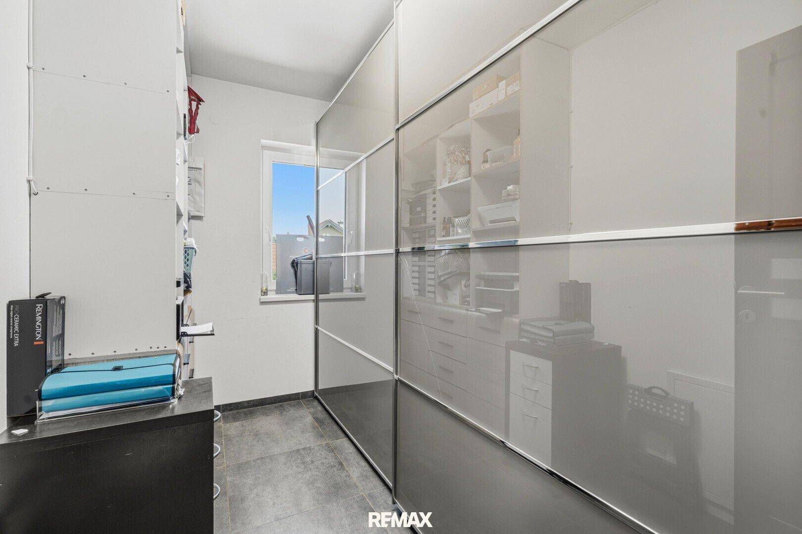 Begehbarer Kleiderschrank mit Regalsystemen, Glasfronten und Fenster.
