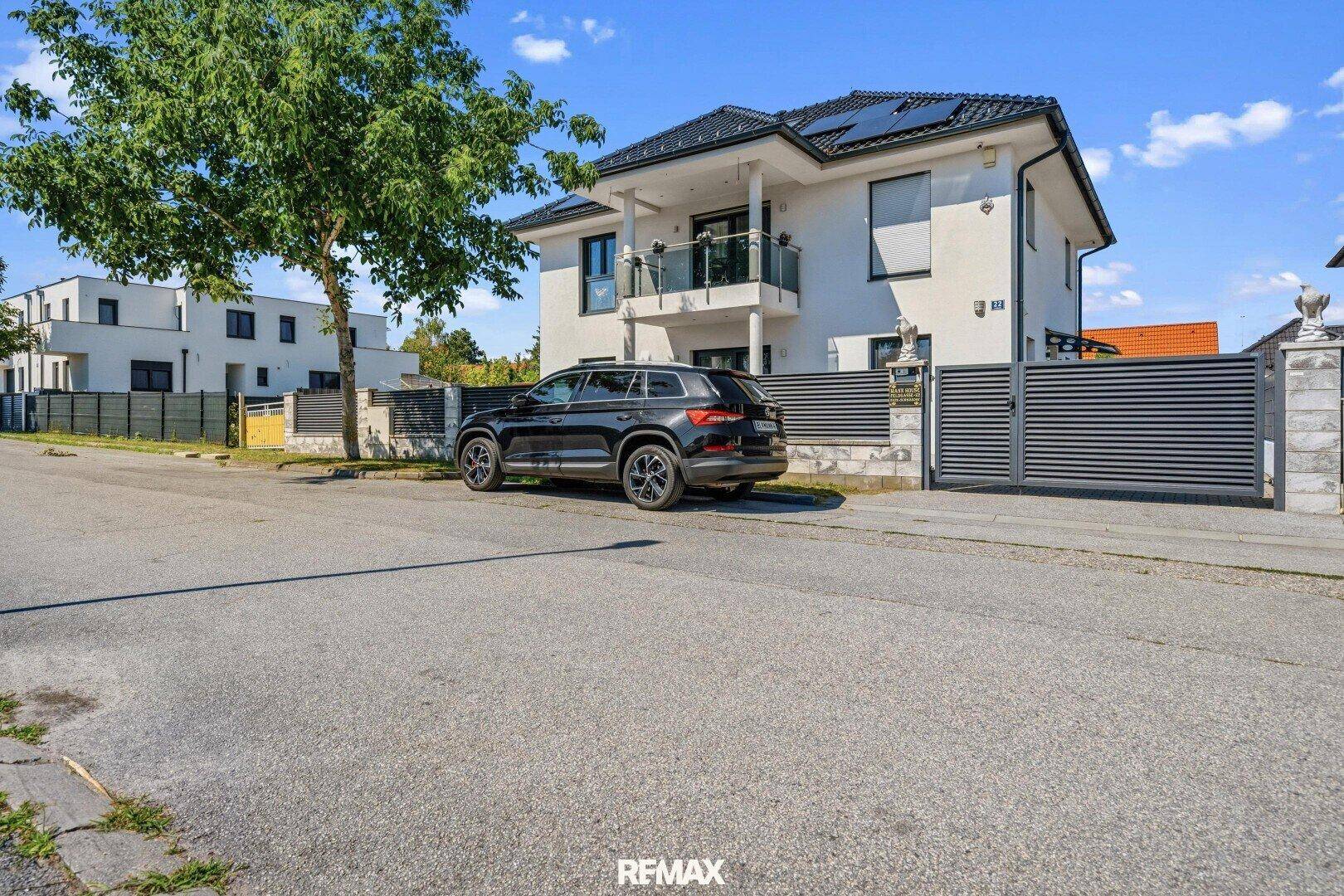 Ansicht des modernen Einfamilienhauses von der Straße mit Einfahrt und gepflegtem Vorgarten.